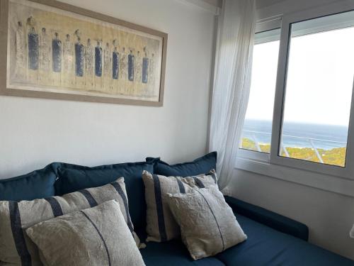 Sofá azul con almohadas en una habitación con ventana en Apartamento en Playa de Pals con encanto y vistas, en Pals
