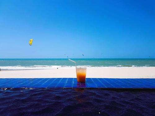 una bebida sentada sobre una alfombra azul en la playa en Varandas Do Mar Modern Deluxe Apartment Beach Front Cumbuco, en Cumbuco