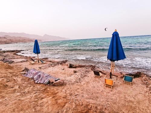 two umbrellas and chairs on a beach with the ocean at Lucky palace Dahab in Dahab