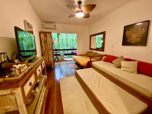 a living room with a couch and a tv at Maresias, Chalé H29 em condomínio de frente a Entrada 18 da praia e dentro da Mata Atlântica in São Sebastião