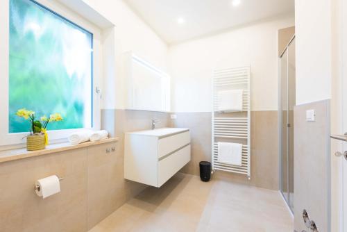 a bathroom with a sink and a shower and a window at Meranosuites - Therme in Merano
