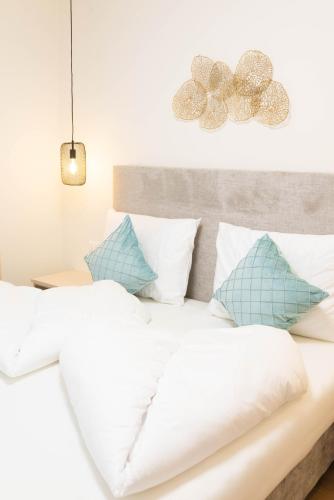a bed with white sheets and blue pillows at Meranosuites - Therme in Merano