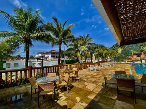 a patio with tables and chairs next to a pool at Maresias, Chalé H29 em condomínio de frente a Entrada 18 da praia e dentro da Mata Atlântica in São Sebastião