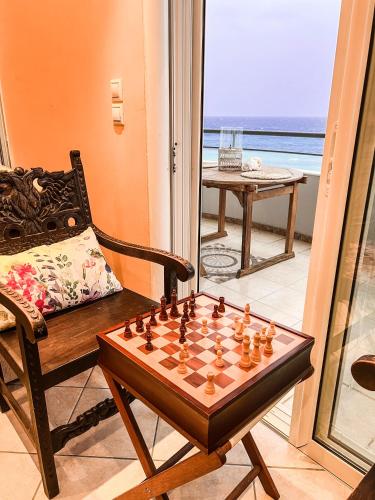 a chessboard and a chair in a room with a window at BLUE CAVE LUXURY MAISONETTE View to the Corinthian Sea in Xylokastron