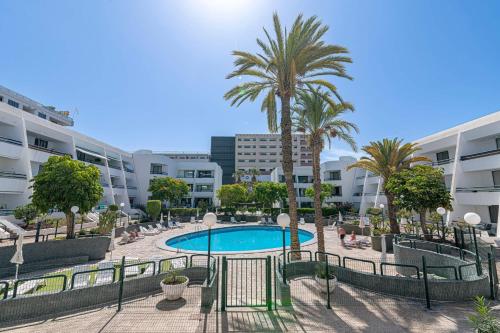 a pool in a courtyard with palm trees and buildings at GO2TENERIFE Apart'Masca Pool view & Beach at 5 min in Playa de las Americas
