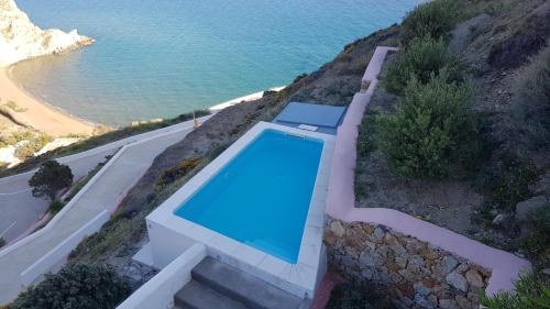 a swimming pool on a hill next to the ocean at Apollon Village Hotel in Anafi