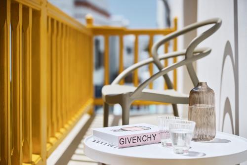 a table with a book and glasses and a chair at Elaia Luxury Suites Mykonos in Mýkonos City