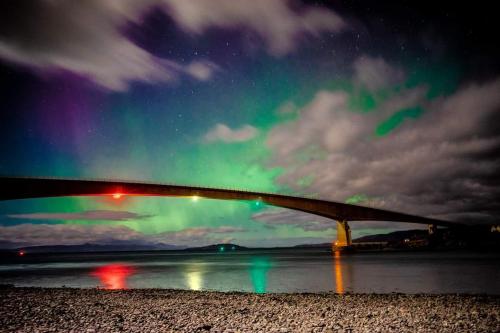 a bridge over the water with the northern lights at The Lodge Dunrowan in Kyle of Lochalsh
