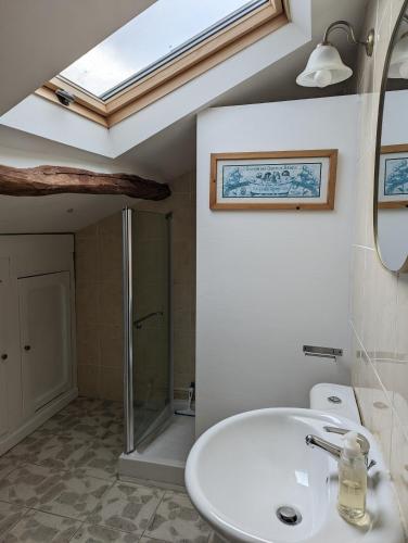 une salle de bain avec un lavabo blanc et une lucarne dans l'établissement Closerie Les Roches - Charming and spacious 2 bedroom cottage, à Bouillé-Loretz