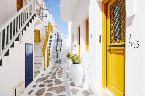 a narrow alley with a yellow door and a vase with a plant at Elaia Luxury Suites Mykonos in Mýkonos City