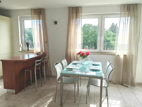 - une salle à manger avec une table et des fleurs dans l'établissement Sea View Apartment & Studio Apartment Bruno Umag, à Umag