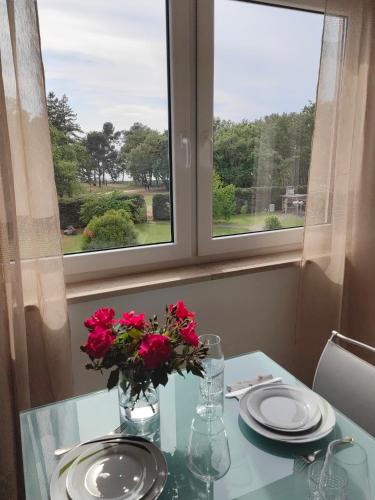 a table with a vase of flowers on a table with a window at Sea View Apartment & Studio Apartment Bruno Umag in Umag