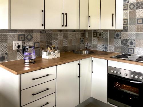 a kitchen with white cabinets and a sink at Harpy Haven in Parys