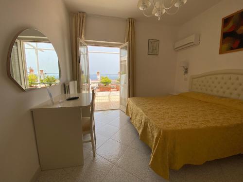 a bedroom with a bed and a desk and a window at Hotel La Perla in Praiano