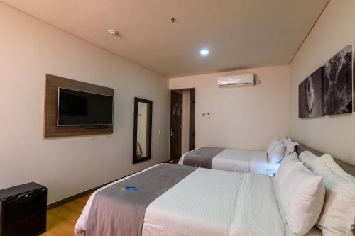 a hotel room with two beds and a flat screen tv at Hotel Vivre in Medellín