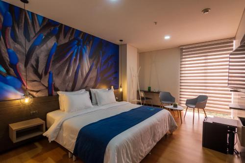 a bedroom with a bed and a painting on the wall at Hotel Vivre in Medellín