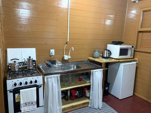 a kitchen with a sink and a stove and a microwave at Cabana Vó Bilica in Urubici