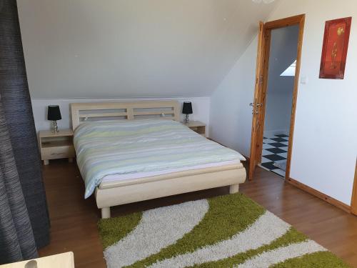 a bedroom with a bed and a green rug at Sunset Holidays - Dom nad Jeziorem in Żarnowska