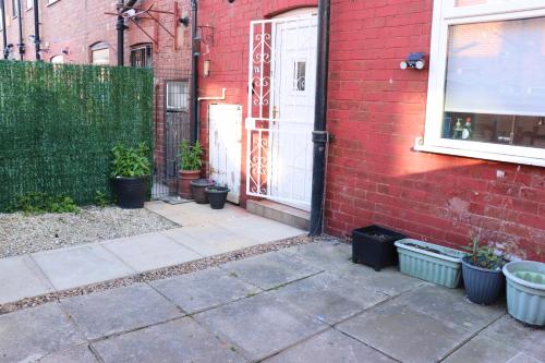uma casa de tijolos vermelhos com uma porta e vasos de plantas em Spacious & Comfortable 3 Bedroom House - FREE WiFi & FREE Parking em Killingbeck