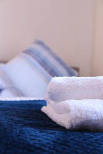 a white towel sitting on top of a bed at Spacious & Comfortable 3 Bedroom House - FREE WiFi & FREE Parking in Killingbeck