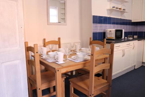 a kitchen with a wooden table with chairs and a tableasteryasteryasteryasteryastery at Spacious & Comfortable 3 Bedroom House - FREE WiFi & FREE Parking in Killingbeck