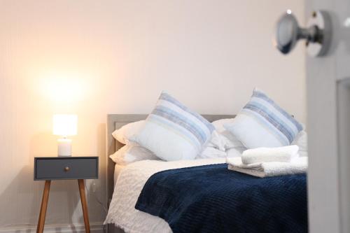 a bedroom with a bed with blue and white pillows at Spacious & Comfortable 3 Bedroom House - FREE WiFi & FREE Parking in Killingbeck