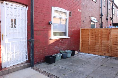 a red brick building with a white gate and a door at Spacious & Comfortable 3 Bedroom House - FREE WiFi & FREE Parking in Killingbeck