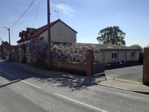 a fence with purple flowers on the side of a house at 14-18 Somme Chambres in Beaucourt-sur-lʼAncre
