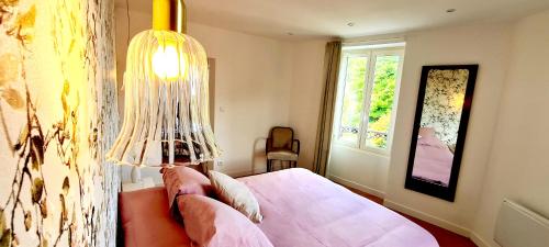 a bedroom with a pink bed and a lamp at L'App'Art d'Auvers in Auvers-sur-Oise