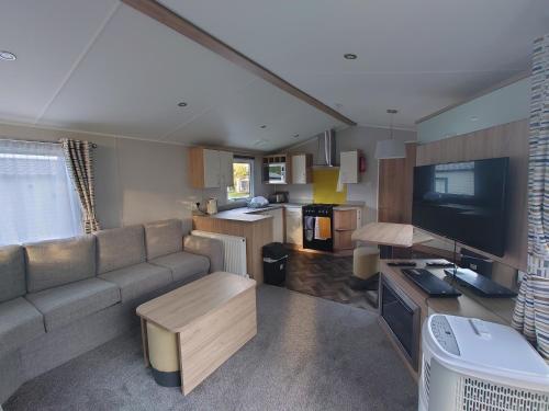 a living room with a couch and a tv at Lakeside Caravan White Acres Holiday Park Newquay Sleeps 6 in Saint Enoder