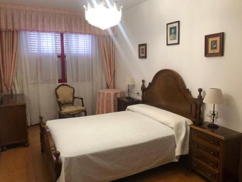 1 dormitorio con 1 cama, 1 silla y 1 lámpara de araña en Piso centro de Raxò, en Raxó