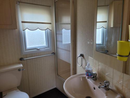 a bathroom with a sink and a toilet and a window at 6 Berth Seaview Ingoldmells Park Lodge in Ingoldmells