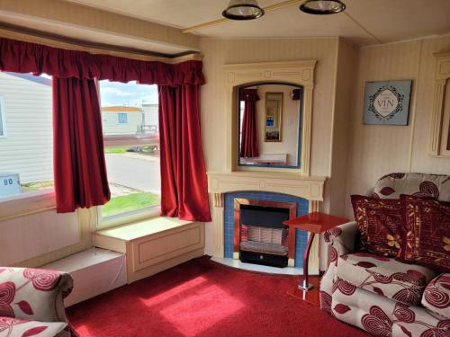 a living room with a fireplace and red curtains at 6 Berth Seaview Ingoldmells Park Lodge in Ingoldmells