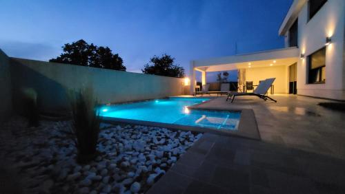 una piscina en el patio trasero de una casa por la noche en Villa Dorina en Kaštel