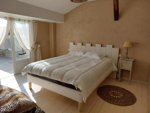a bedroom with a large white bed in a room at L'Appartement de la MAISON BLEUE in Villeréal