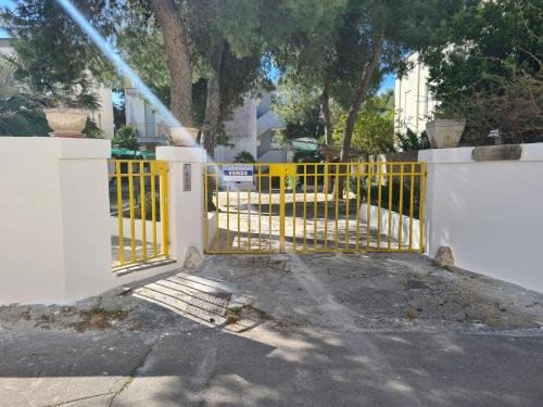 a yellow gate in front of a white fence at Dimora dei pini in Leuca