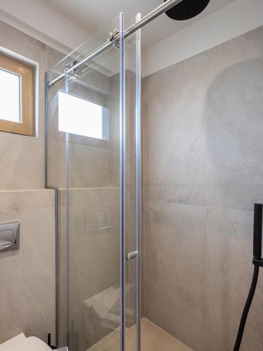 a shower with a glass door in a bathroom at Esperides Beach Hotel Apartments in Stalos