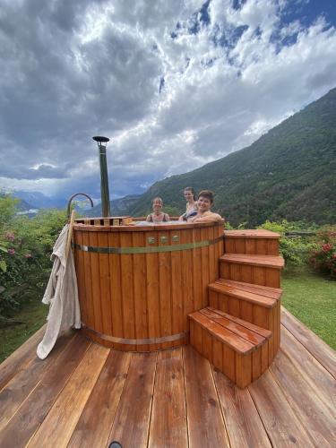 three people in a wooden hot tub on a deck at Maison Perriere - Chambres d'hôtes & Jacuzzi in Saint Vincent