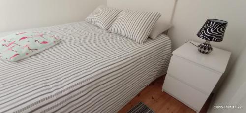 a bedroom with a bed and a nightstand with a lamp at Largo da Paz 24 in Lisbon