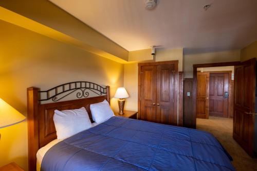 um quarto com uma cama com um edredão azul em Highland House 207 Slopeside, Village Area, Ski in out em Snowshoe