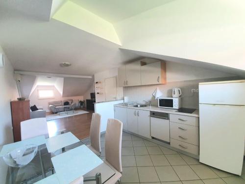 Una cocina con gabinetes blancos y una mesa con sillas. en Apartment Lily near Zagreb airport, en Velika Gorica