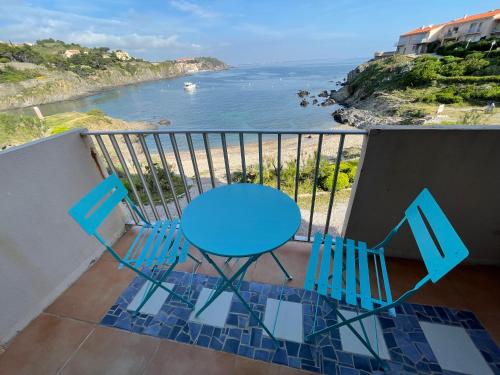 d'une table bleue et de chaises sur un balcon donnant sur l'océan. dans l'établissement AZUR-Les pieds dans l'eau-Vue sur Mer et Clocher de Collioure en toile de fond - WIFI FIBRE- PARKING Couvert, à Collioure