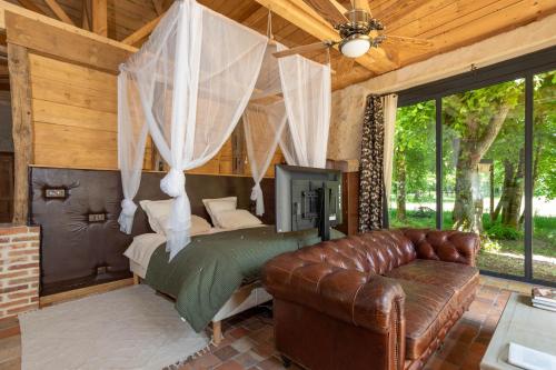 a bedroom with a bed and a leather couch at Manoir de la Mazeraie lodge de luxe Loire Valley in Joue-les-Tours
