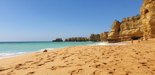 people walking on a sandy beach next to the ocean at Apartamento Salgados Beach in Albufeira