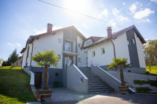 a white house with palm trees in front of it at Apartmani San Martin in Sveti Martin na Muri