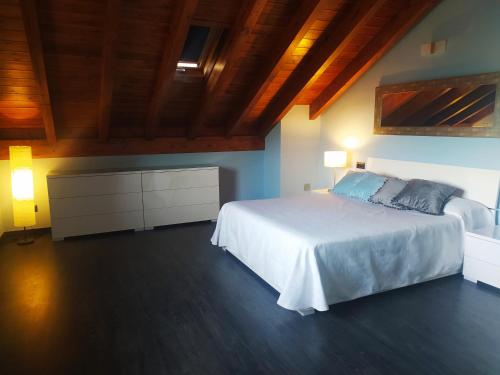 1 dormitorio con cama blanca y techo de madera en Casa Rural Tejedor, en Morillo de Monclús