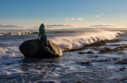 a woman sitting on a rock in the ocean at Cuillich Mill Bed and Breakfast in the Highlands in Alness