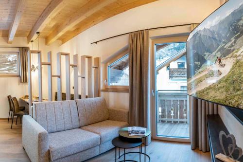 a living room with a couch and a large window at ROSENHOF- Premium & Landhaus Apartments & Wellness & Erlebnisbauernhof in Nauders