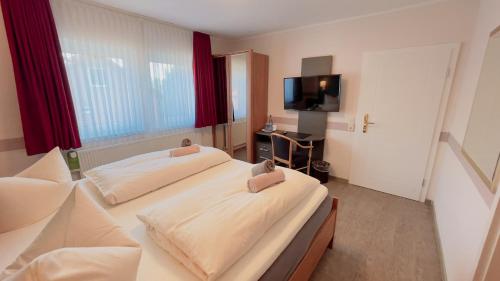 a hotel room with two beds and a flat screen tv at Hotel Schnehagen in Bad Fallingbostel