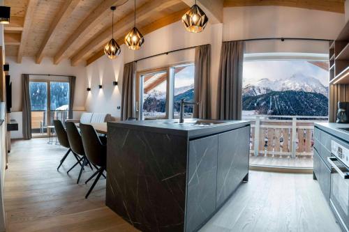 a kitchen with a large window and a table with chairs at ROSENHOF- Premium & Landhaus Apartments & Wellness & Erlebnisbauernhof in Nauders